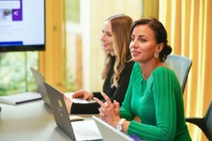 return to office two women sitting at a table with a laptop
